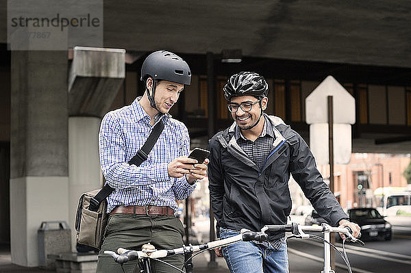 Multi-ethnische männliche Pendler mit Smartphone auf der Straße in der Stadt
