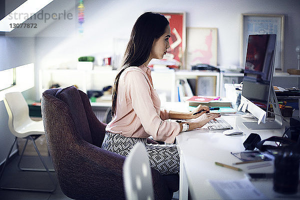 Geschäftsfrau  die am Computer am Schreibtisch im Kreativbüro arbeitet