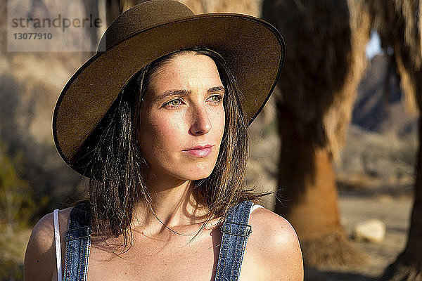 Nachdenkliche junge Frau mit Hut beim Blick in die Wüste