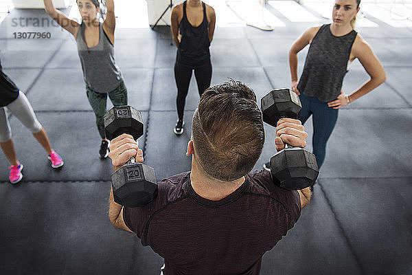 Instrukteurin erklärt Athleten das Hanteln-Heben in einer Crossfit-Turnhalle