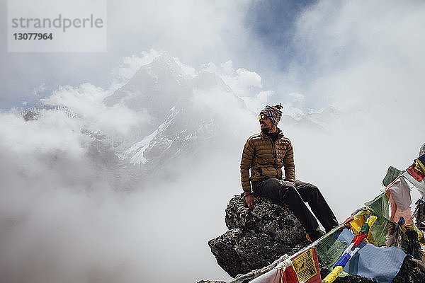 Wanderer sitzt auf Berg gegen bewölkten Himmel im Sagarmatha-Nationalpark