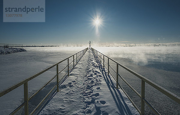 Schneebedeckter Pier über dem See gegen den Himmel