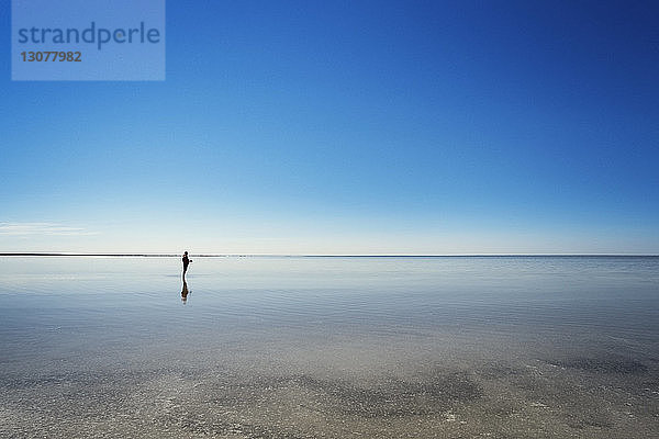 Mitteldistanz eines Mannes  der am Strand vor klarem blauen Himmel steht