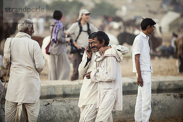 Mann telefoniert im Gehen mit Freund auf der Pushkar-Messe