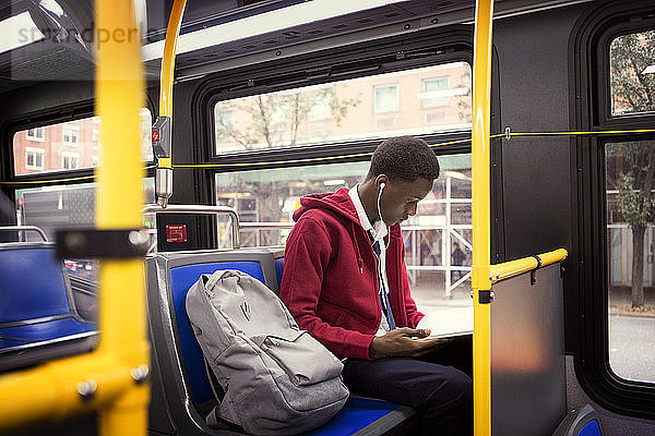 Student hört Musik und liest ein Buch  während er im Bus sitzt