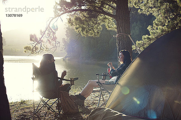 Freundinnen entspannen sich an sonnigen Tagen auf einem Campingplatz am See