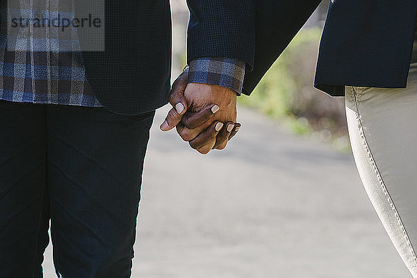 Ausgeschnittenes Bild eines Paares  das beim Spaziergang im Park Händchen hält