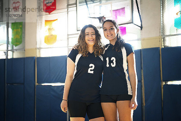Porträt von lächelnden Teenager-Mädchen  die auf dem Volleyballfeld stehen