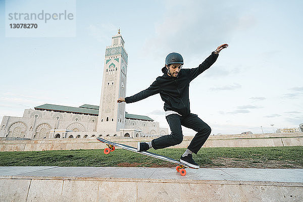 Mann in voller Länge mit Skateboard-Stunt gegen Moschee Hassan II