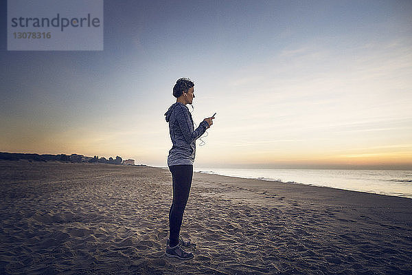 Frau in voller Länge beim Telefonieren am Strand