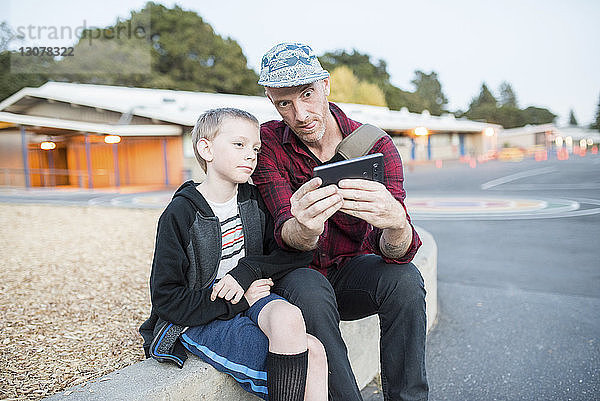 Vater und Sohn unterhalten sich auf der Straße per Handy über Selbstgespräche