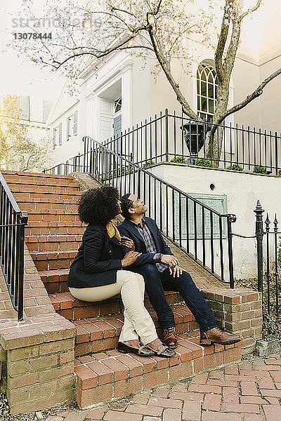Ehepaar schaut auf  während es auf Stufen sitzt