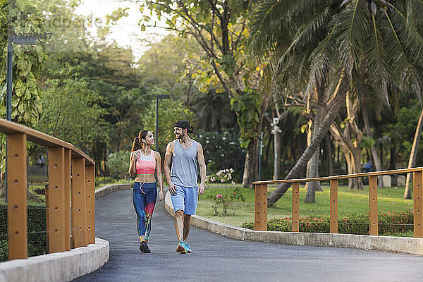 Lächelndes Paar redet und geht auf der Straße im Park