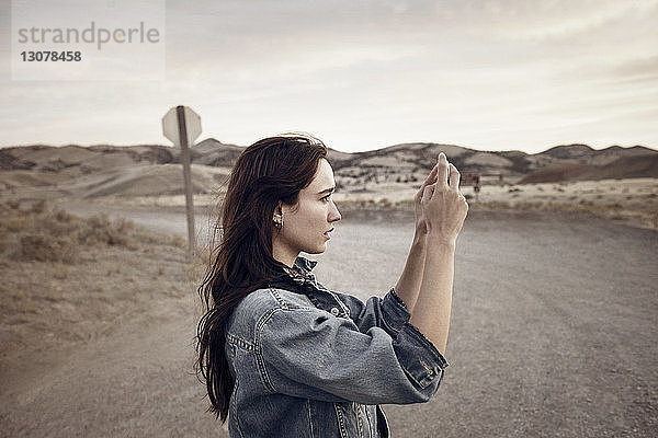 Frau fotografiert  während sie auf dem Feld gegen den Himmel steht