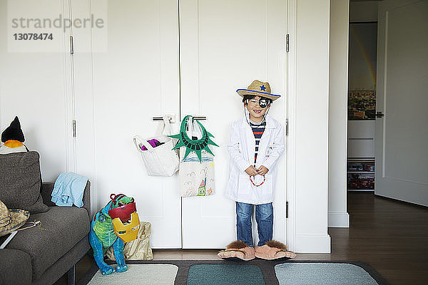 Glücklicher Junge im Kostüm  der zu Hause gegen den Schrank steht