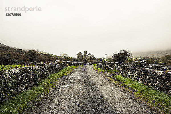 Leere Straße inmitten einer Steinmauer gegen den Himmel bei nebligem Wetter