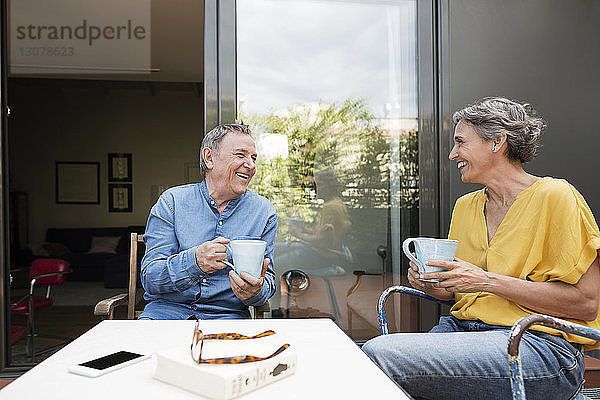 Glückliches älteres Ehepaar trinkt Kaffee auf der Veranda