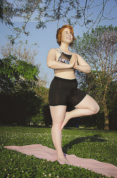 Tiefwinkelansicht einer Frau  die im Park Baumpose-Yoga praktiziert