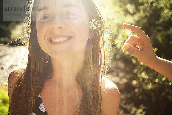 Lächelndes Mädchen mit Blumen im Wald an einem sonnigen Tag