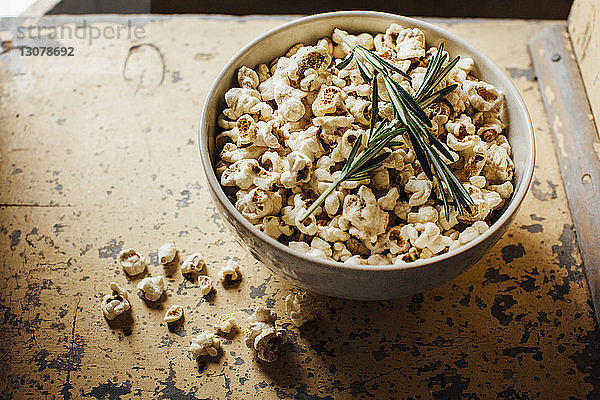 Hochwinkelansicht von Popcorn und Rosmarin in einer Schale auf dem Tisch