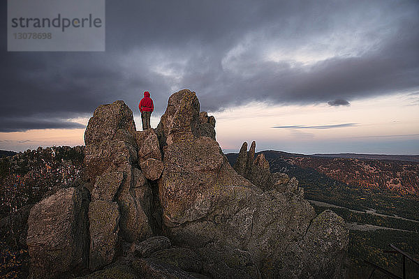 Weibliche Wanderin steht auf Berg vor bewölktem Himmel