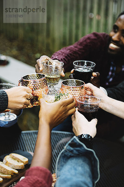Ausgeschnittenes Bild von Freunden  die im Hinterhof sitzen und auf Getränke anstoßen