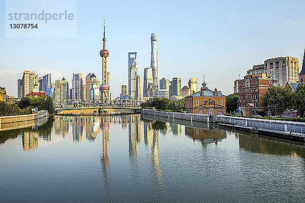 Moderne Gebäude am Huangpu-Fluss vor blauem Himmel bei Sonnenuntergang