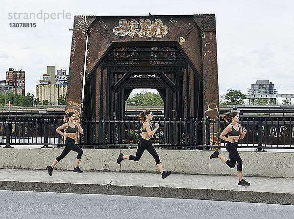 Sportliche Frau joggt beim Training auf der Brücke in der Stadt