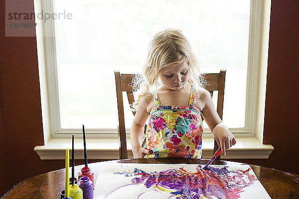 Mädchen malen Papier gegen Fenster zu Hause