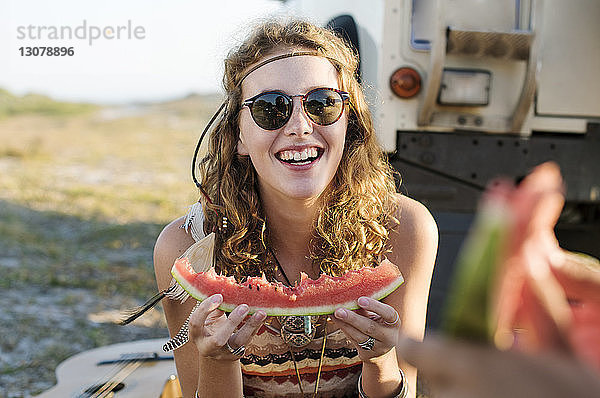 Glückliche Frau isst Wassermelone am Strand