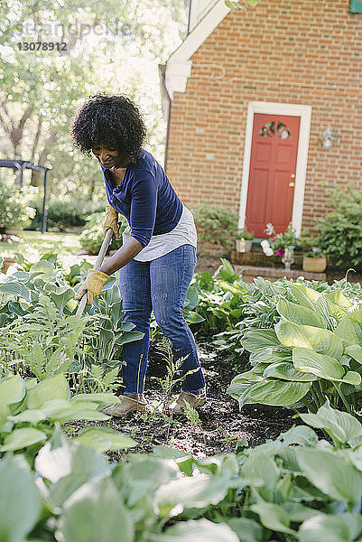 Frau benutzt Gartengabel bei der Gartenarbeit