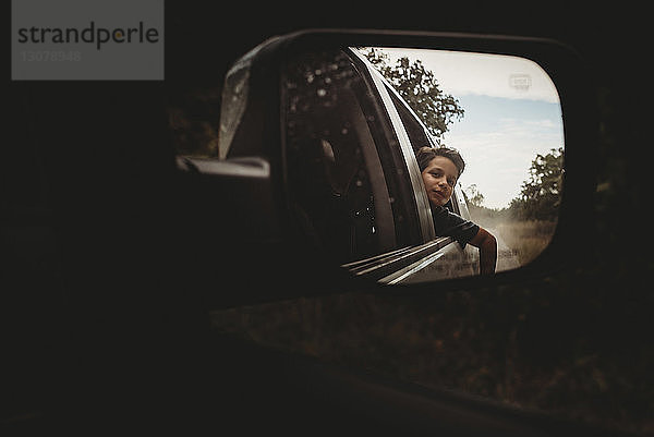 Spiegelung eines Teenagers im Seitenspiegel eines Autos