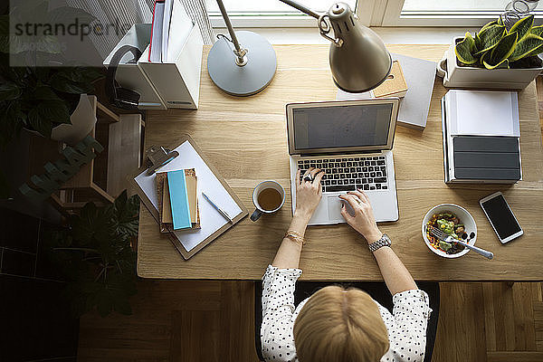 Draufsicht einer Frau mit Laptop am Tisch im Heimbüro