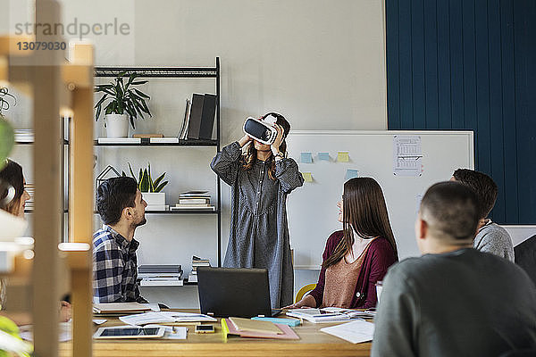 Freunde schauen Studenten an  die einen Virtual-Reality-Simulator benutzen  während sie im Klassenzimmer sitzen