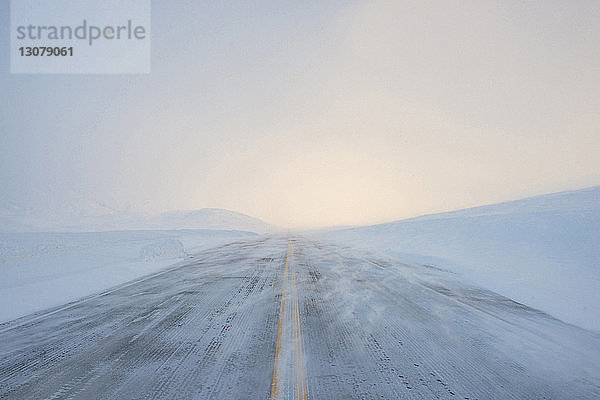 Ansicht einer schneebedeckten Straße gegen den Himmel bei Nebelwetter