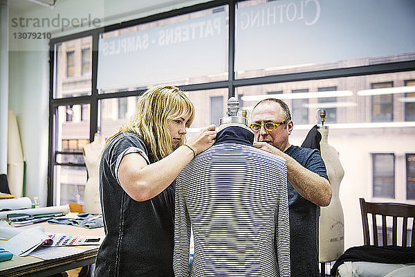 Modedesigner arbeiten im Designstudio an Jacke gegen Glasfenster