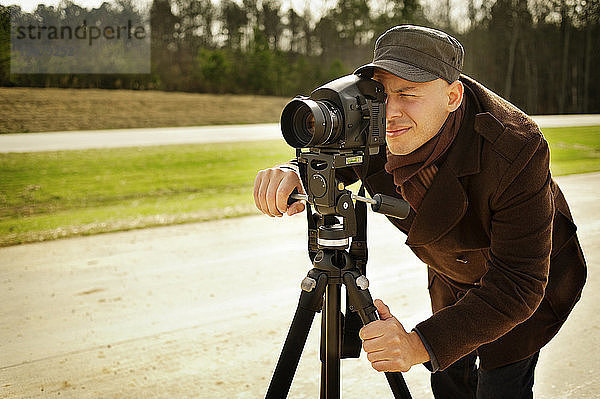 Fotograf mit Stativ auf Straße gegen Wald