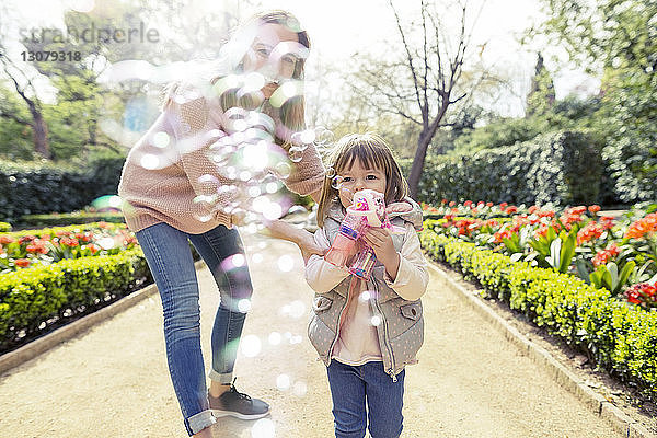 Mutter und Tochter spielen mit Blasenpistole im Park