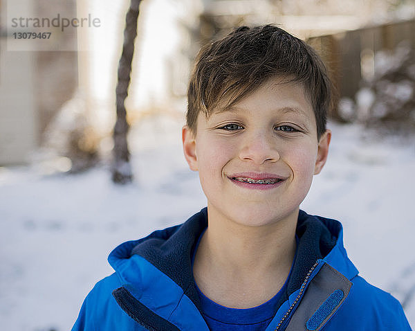 Porträt eines lächelnden Jungen mit Zahnspange  der im Winter warme Kleidung trägt