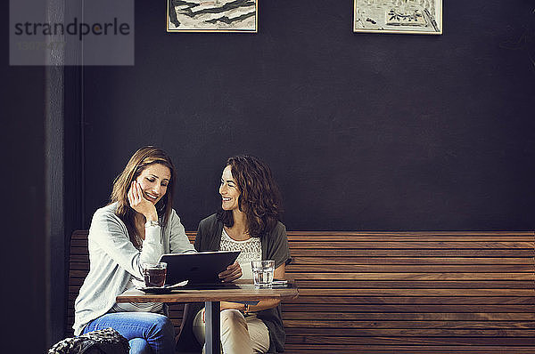 Glückliche Freundinnen mit Tablet-Computer im Café