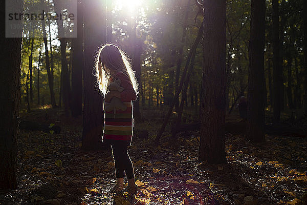 Seitenansicht eines im Wald stehenden Mädchens