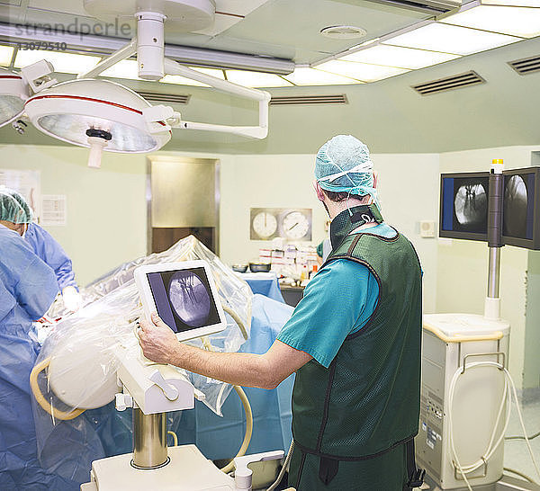 Rückansicht eines Chirurgen  der mit Kollegen im Operationssaal arbeitet