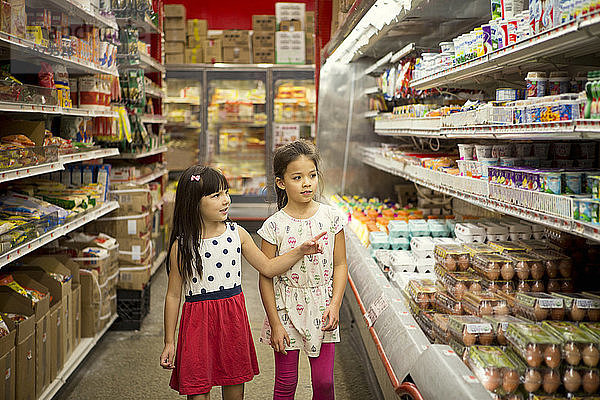Mädchen schauen sich verschiedene Produkte in den Regalen des Supermarktes an