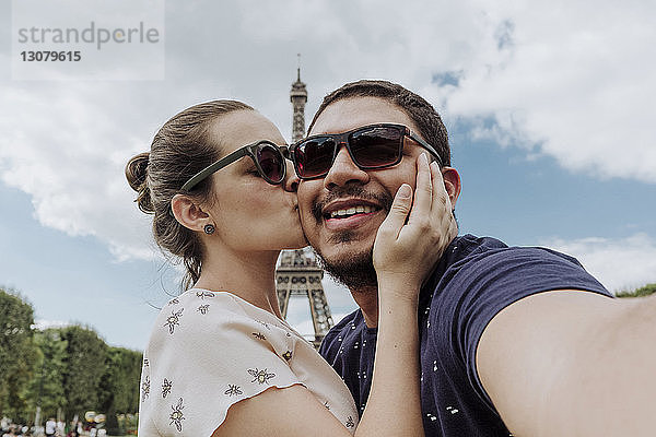 Porträt einer Freundin  die ihren Freund gegen den Eiffelturm in der Stadt küsst