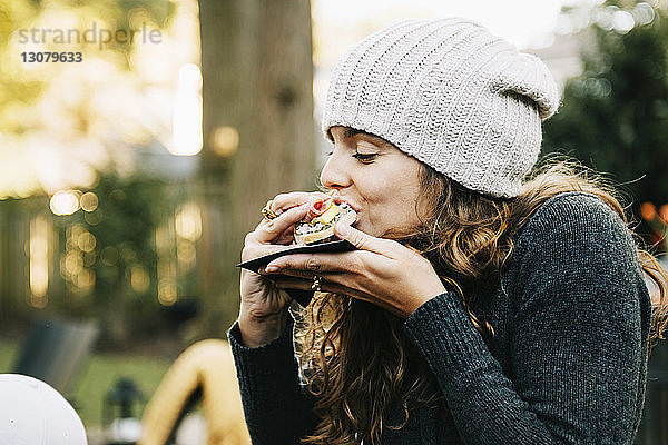 Frau isst Sandwich  während sie im Hinterhof sitzt