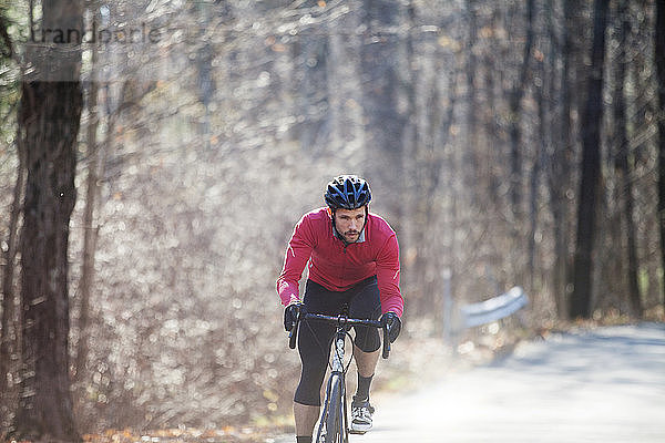 Fahrrad fahrender männlicher Radfahrer auf Straße im Wald