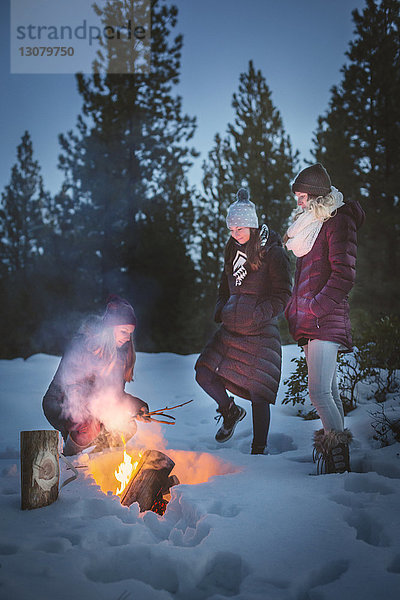 Freundinnen machen Lagerfeuer auf schneebedecktem Feld