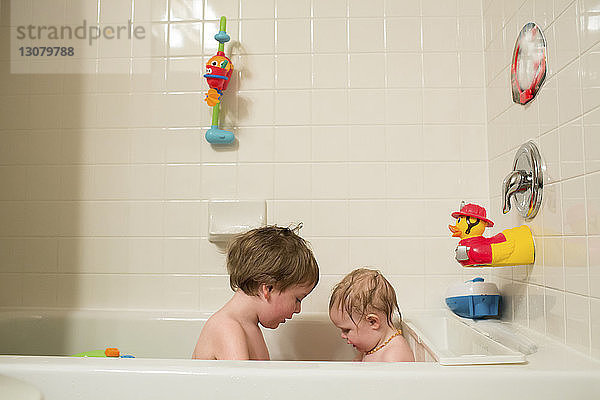 Geschwister sitzen zu Hause in der Badewanne