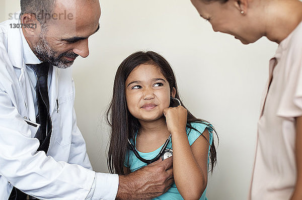 Mutter und Arzt sehen Mädchen an und hören Herzschläge im medizinischen Untersuchungsraum