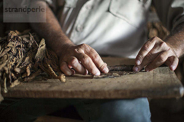 Mittelsektion eines Mannes  der im Workshop trockene Blätter auf den Tisch rollt